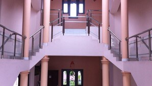 Un interior de varios niveles con una escalera, columnas y una araña.