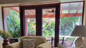 Una sala de estar con un sofá color beige, un sofá estampado, una mesa de centro de madera y una planta en maceta.