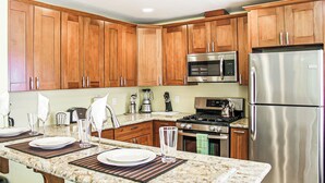 A kitchen with wooden cabinets, stainless steel appliances, and a granite countertop. - Luxury Ocean View, Across from the Beach #5 (Carlsbad)
