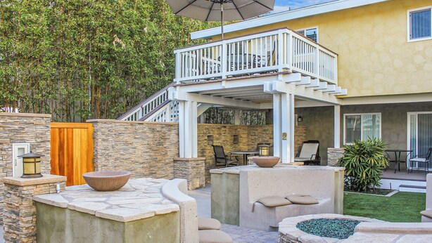 A patio area with stone planters, outdoor furniture, and a staircase leading to an upper deck. - Luxury Ocean View, Across from the Beach #5 (Carlsbad)