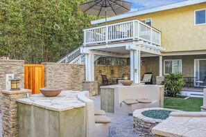A patio area with stone planters, outdoor furniture, and a staircase leading to an upper deck. - Luxury Ocean View, Across from the Beach #5 (Carlsbad)