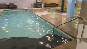 Ein Schwimmbecken mit Metallleiter, Sitzbereich und einer Wand mit Uhr.
