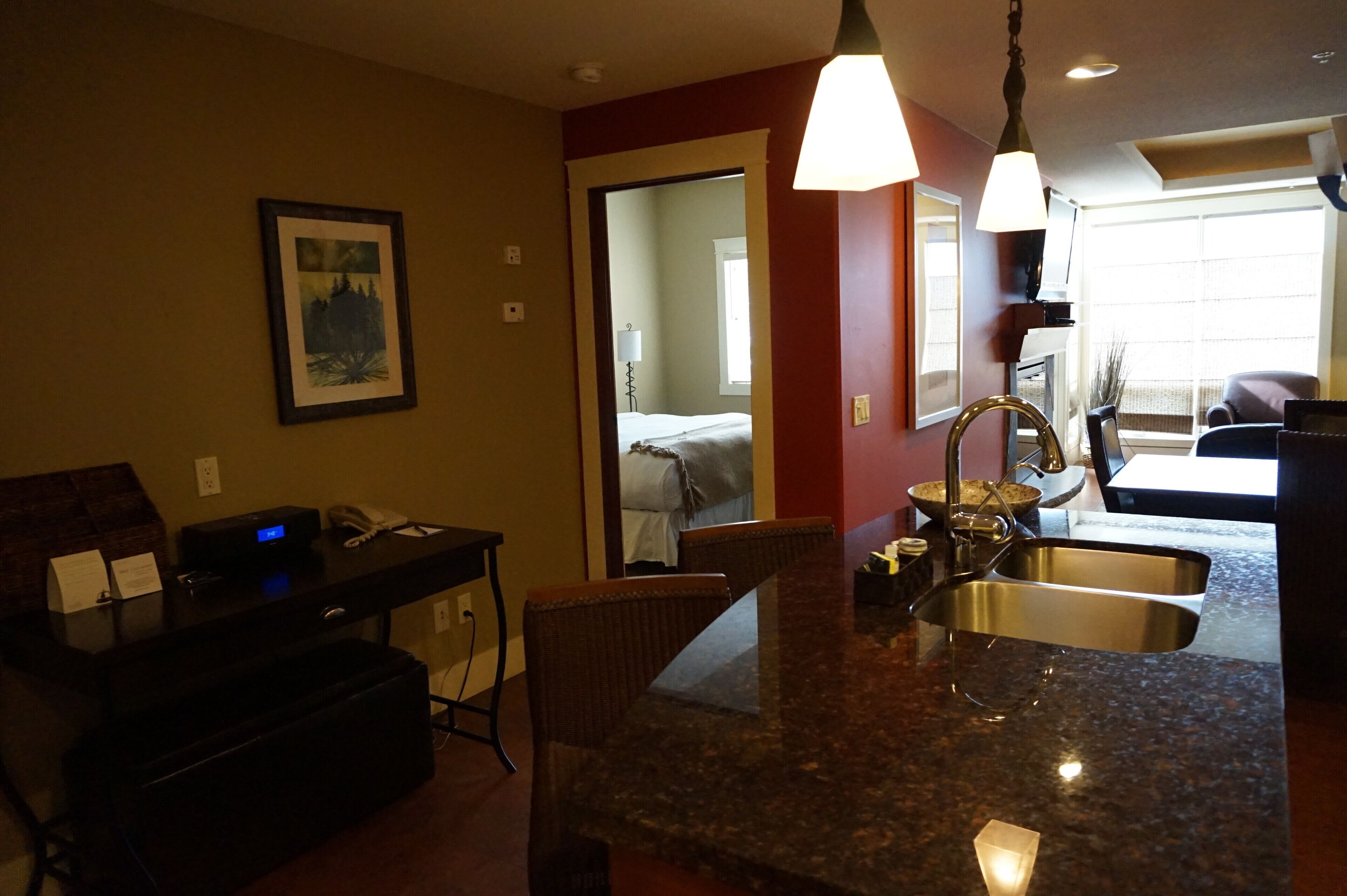 A hotel room with a kitchenette, a dining area, and a bed.