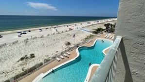 A poolside view with a beach and ocean in the background.
