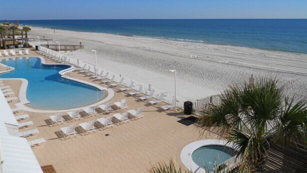A resort pool area with multiple pools, a beach, and lounge chairs.