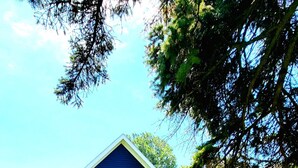Une maison bleue avec une terrasse, un espace salon extérieur et un foyer.