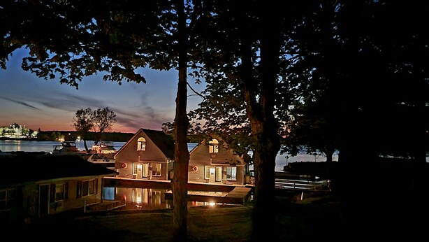 Une propriété située au bord de l’eau, comprenant une maison et un quai, le tout entouré d’arbres.