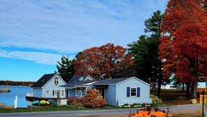 Une maison avec un quai, des feuilles d’automne et des citrouilles.
