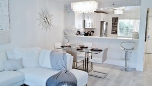Un espace de salle à manger moderne avec une table en verre, des chaises blanches et un lustre.