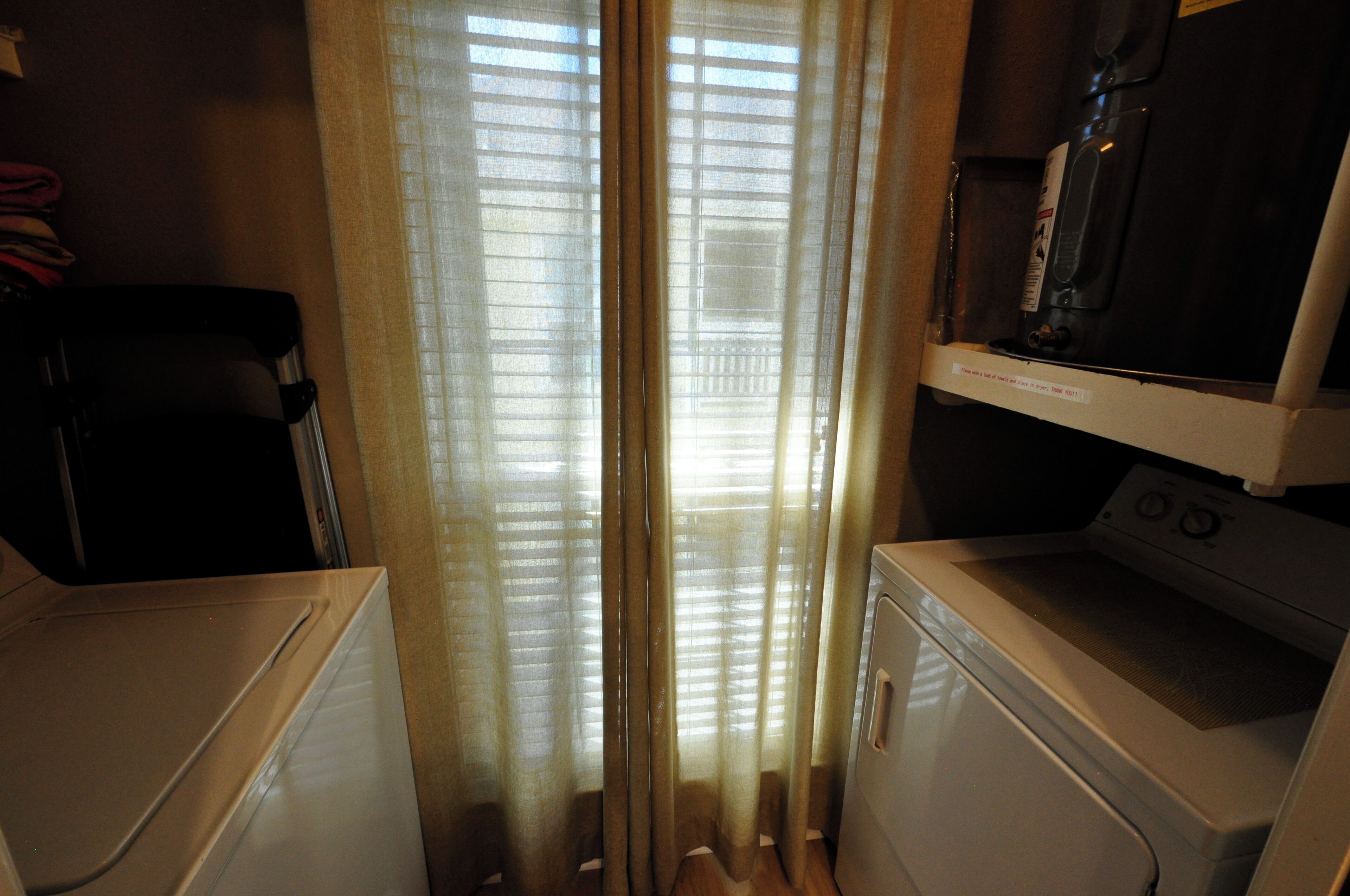 A compact room with a washing machine, a dryer, and a small television on a shelf.