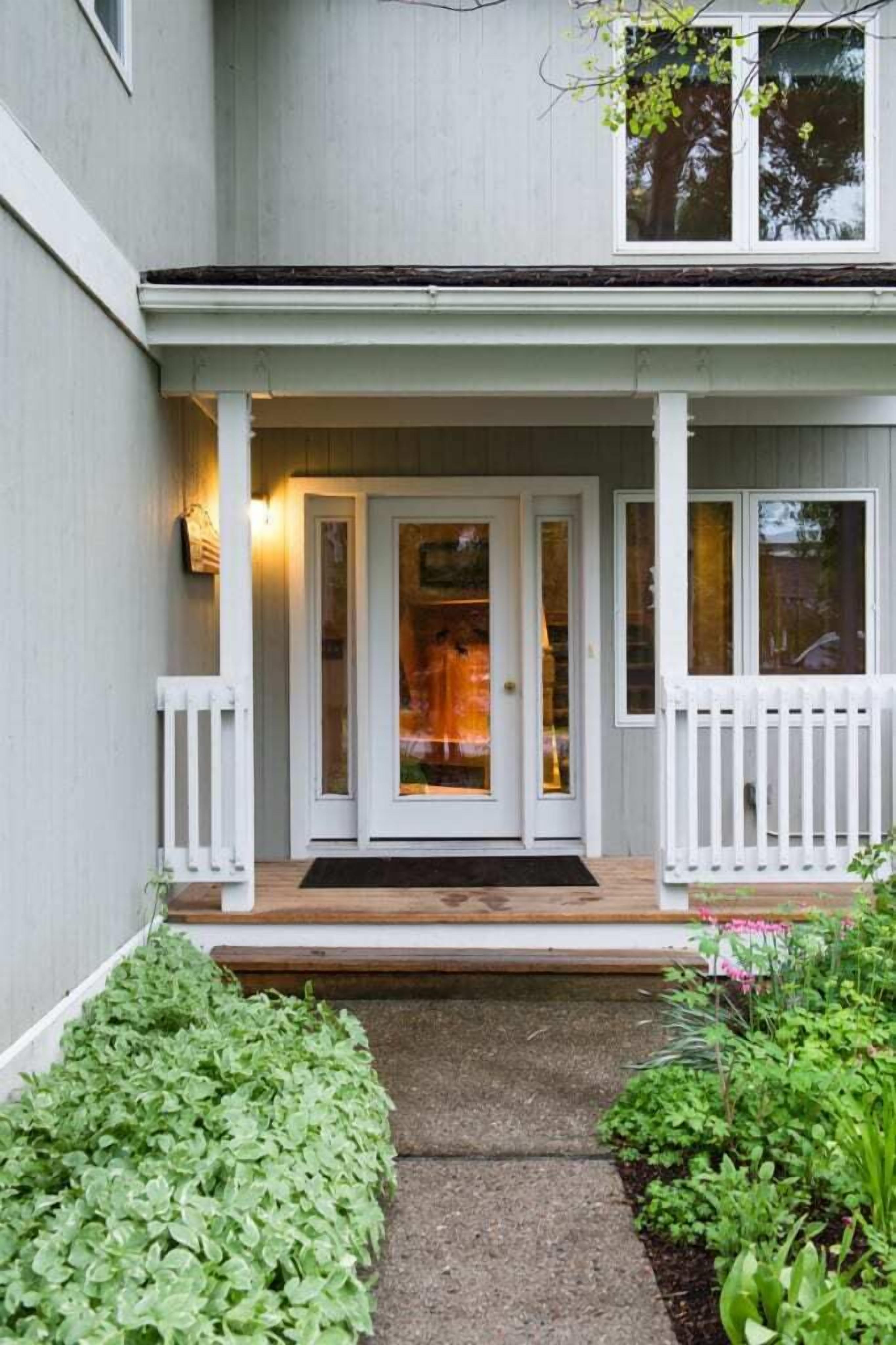 A house with a front porch, a door with glass panels, and a small garden area.