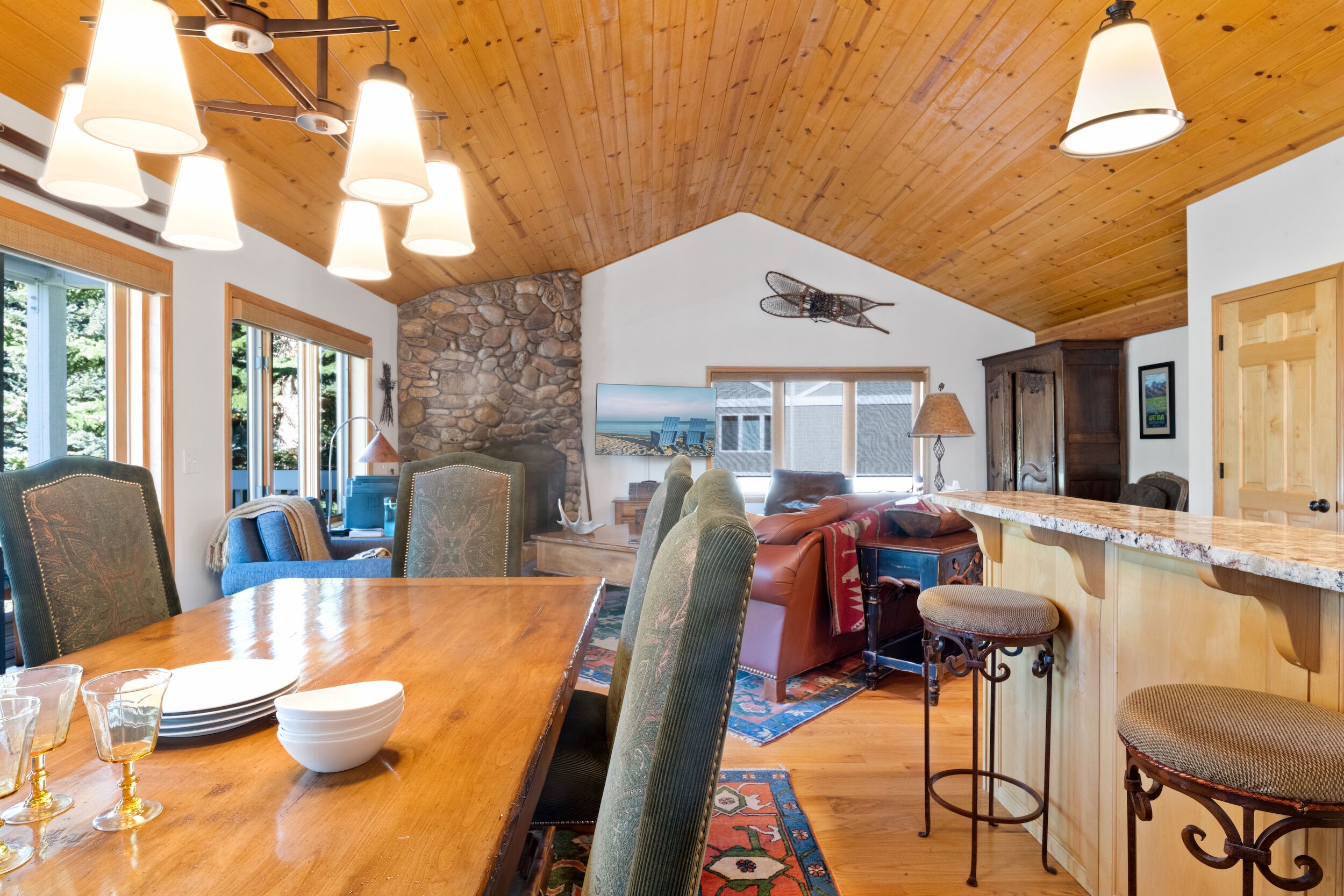A spacious dining area with a wooden table, chairs, and a stone accent wall.