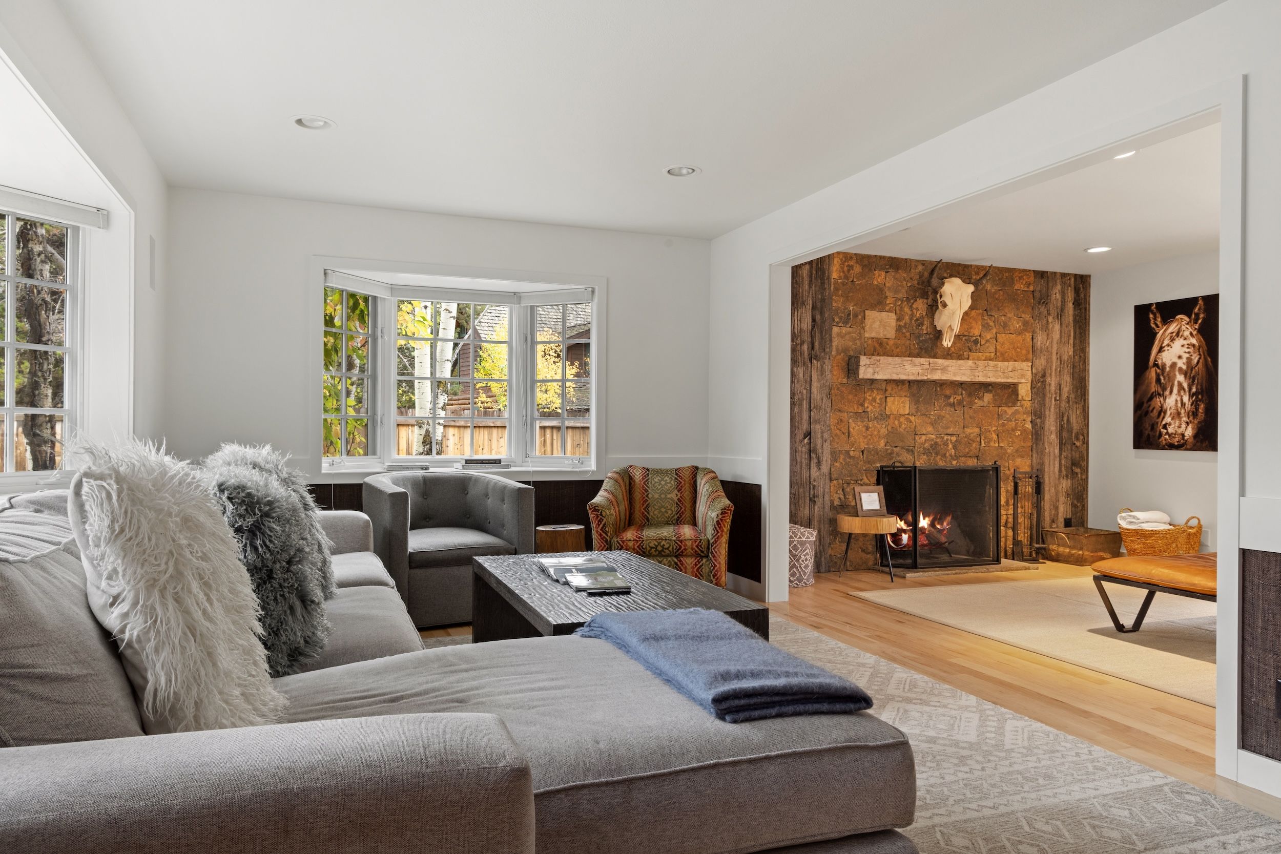 A modern living room with a fireplace, a sofa, a coffee table, and a patterned armchair.