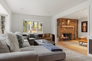 A modern living room with a fireplace, a sofa, a coffee table, and a patterned armchair.