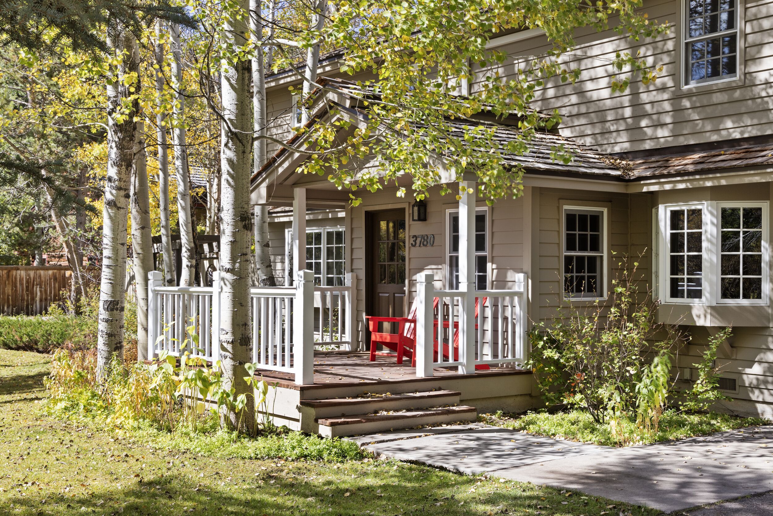 A two-story house with a porch, a red chair, and a mailbox marked "3780".