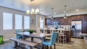 Une cuisine moderne avec des meubles en bois, des appareils électroménagers en acier inoxydable et des luminaires suspendus.