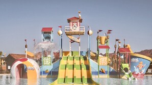 Un parc aquatique doté d’un toboggan central, de nombreuses aires de jeux et d’une décoration sur le thème d’un ballon de plage.