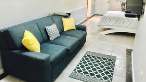 Un espacio habitable pequeño con un sofá, una alfombra estampada y un televisor.