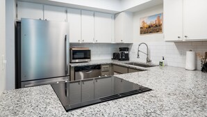 Una cocina moderna con gabinetes blancos, electrodomésticos de acero inoxidable, una encimera de granito y un tragaluz.