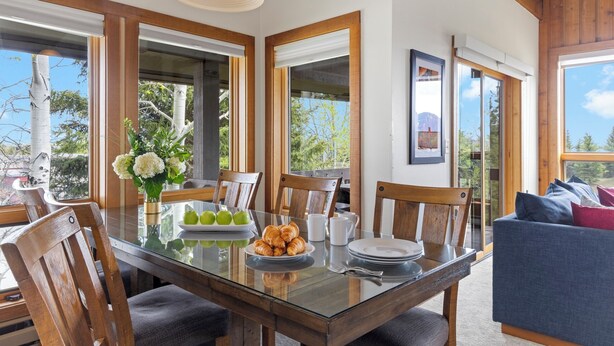 A dining area with a glass table, wooden chairs, and a blue sofa. - Outpost: Nez Perce D5- Hot Tub Access (Teton Village)