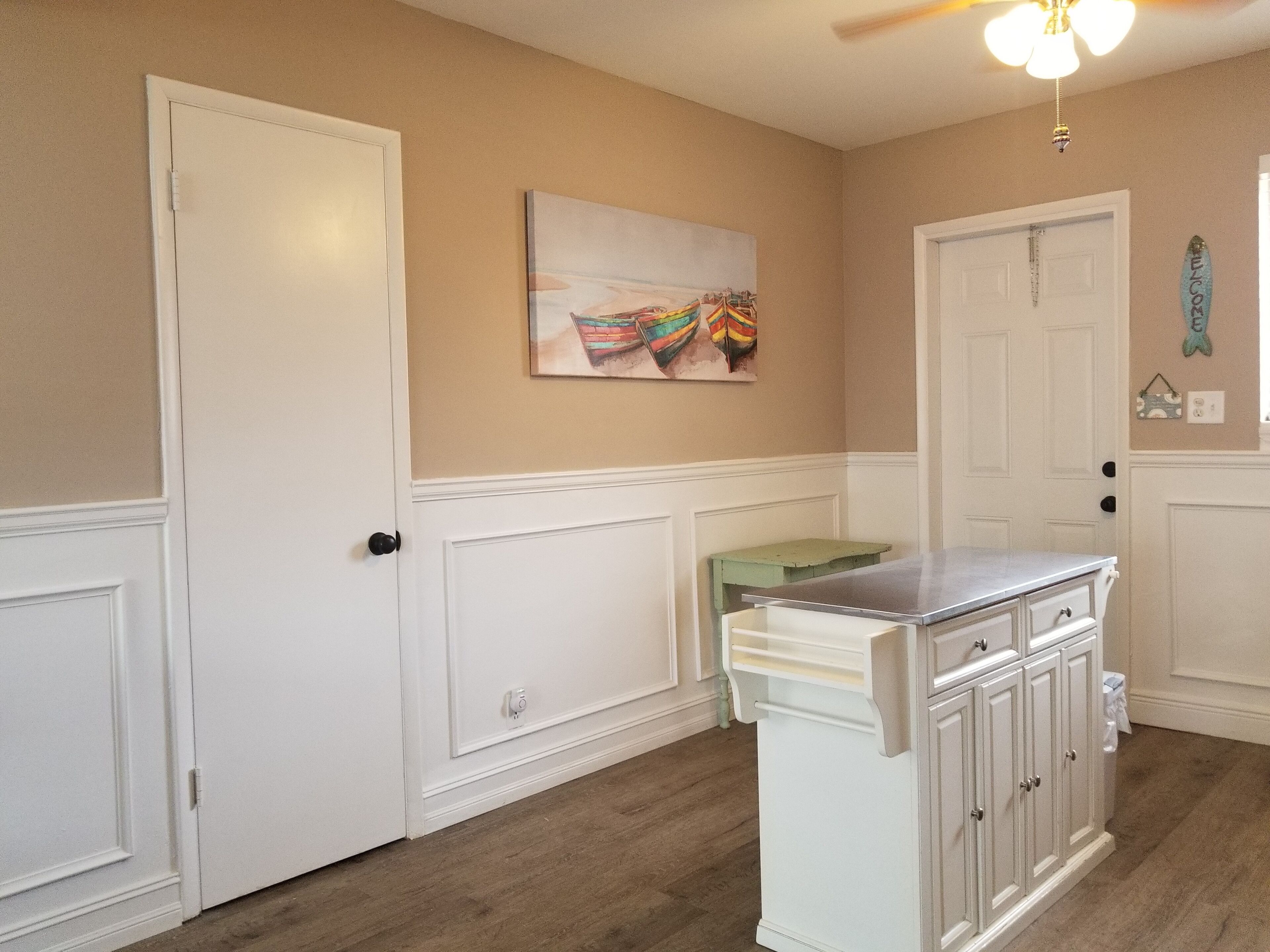A kitchen with white cabinetry, a wooden countertop, and a painting on the wall.