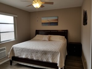 A bedroom with a bed, a ceiling fan, a window, and a painting on the wall. - Beach block cottage with putting green, Everything  needed for a great vacation. (Pompano Beach)