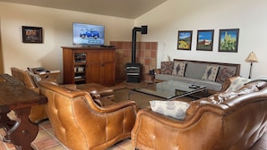 Una sala de estar con sofás de cuero, una mesa de centro de vidrio, un televisor y una chimenea.