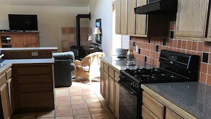 Una cocina con armarios de madera, una estufa negra y suelo de baldosas.