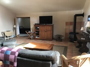 Una sala de estar con sofá, aparador de madera, televisor, chimenea y mesa de comedor.