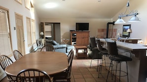 Una cocina amplia con comedor, barra y zona de estar con sofá y televisión.