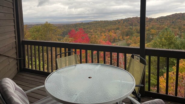 A balcony with a glass table and chairs, overlooking a forested landscape with autumn foliage. - Winterplace Condo D303 (Ghent)