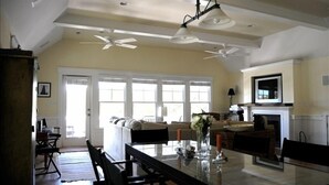 A spacious living room with a large dining table, a fireplace, and a ceiling fan.
