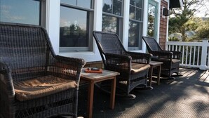 A covered porch with wicker furniture and a small table.