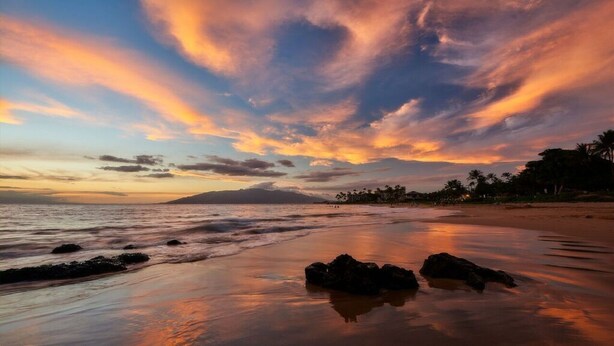 A beach with calm waters, a sunset, and a clear sky. - Steps to beach! Beautiful renovated 1 bedroom (Kihei)