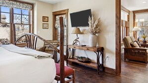 Een kamer met een bed, houten meubels, een televisie en een raam met uitzicht op bomen.