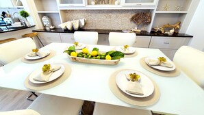 A dining table set with white plates, napkins, and a centerpiece of lemons and green leaves. - POSHPADZ - Sandpiper Villa - Walk to Jupiter Beach (Jupiter)