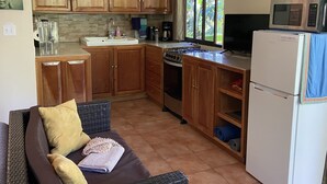 Une cuisine de taille réduite, dotée de meubles en bois, d’une cuisinière à gaz, d’un évier et d’un réfrigérateur.