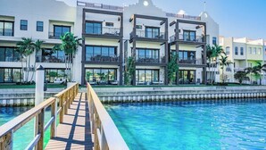 Ein mehrstöckiges Hotel mit Balkonen, einem Pool und einer Holzterrasse.