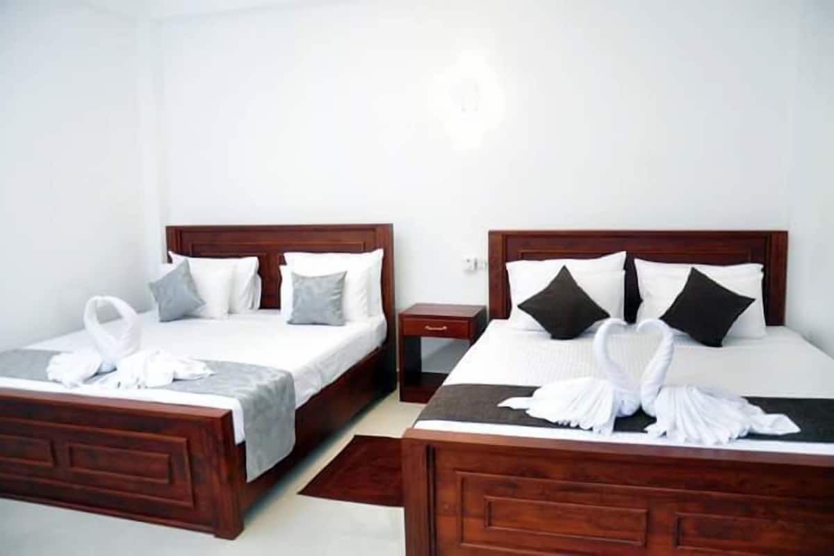Two double beds with wooden headboards, white bedding, and black and white pillows.
