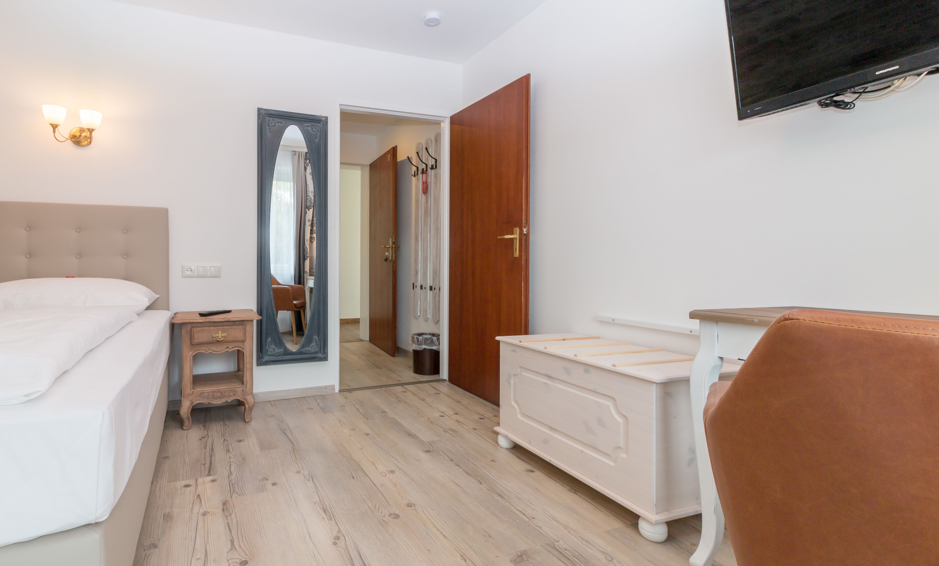 Une chambre d’hôtel comprenant un lit, une commode, une chaise, un miroir et un téléviseur.