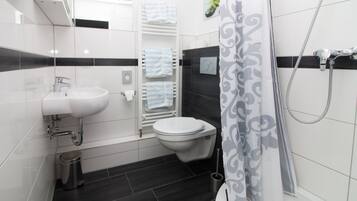 Un baño moderno con lavamanos, inodoro y ducha blancos.