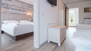 Un dormitorio moderno con una cama, un aparador y un televisor montado en la pared.