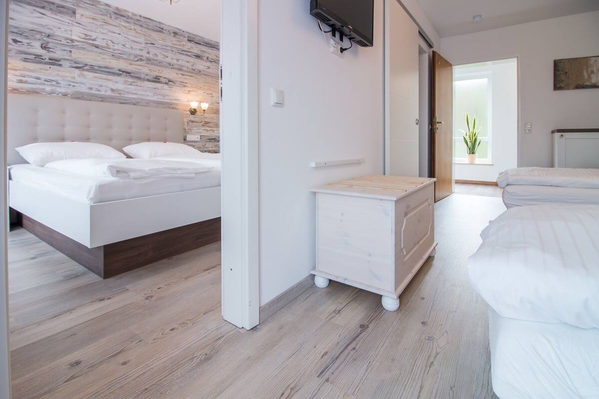 A modern bedroom with a bed, a dresser, and a television mounted on the wall.