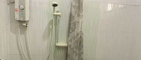 A bathroom with a shower, toilet, and a wall-mounted water heater.