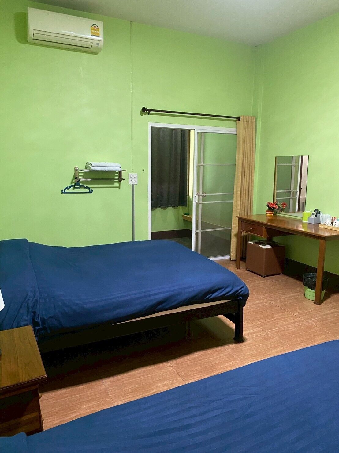 Una habitación con cama, escritorio, espejo, armario y aire acondicionado.