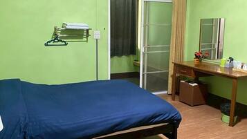 Una habitación con cama, escritorio, espejo, armario y aire acondicionado.