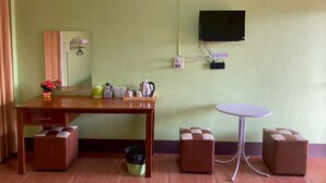A room with a wooden desk, a small round table, and two brown ottomans. - Kanoktid Place (Fang)