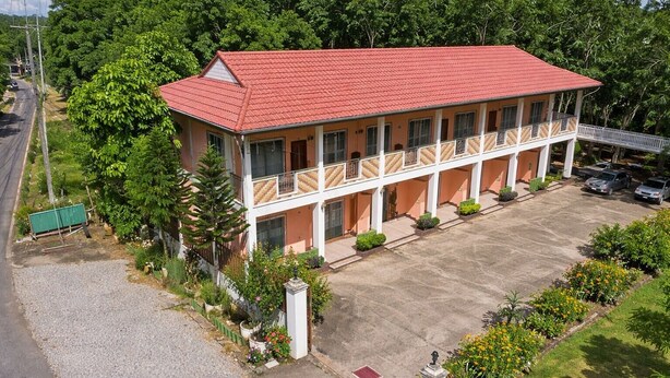 A two-story motel with a red roof, multiple balconies, and a parking lot. - Kanoktid Place (Fang)