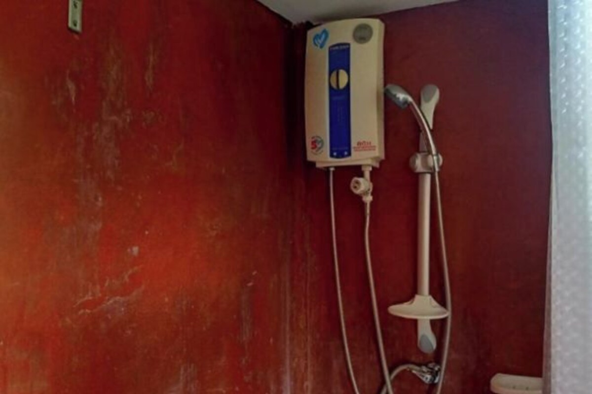A shower with a handheld showerhead and a wall-mounted control panel.