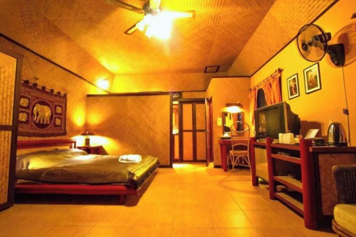 A room with a bed, a desk, a chair, a television, and a ceiling fan.
